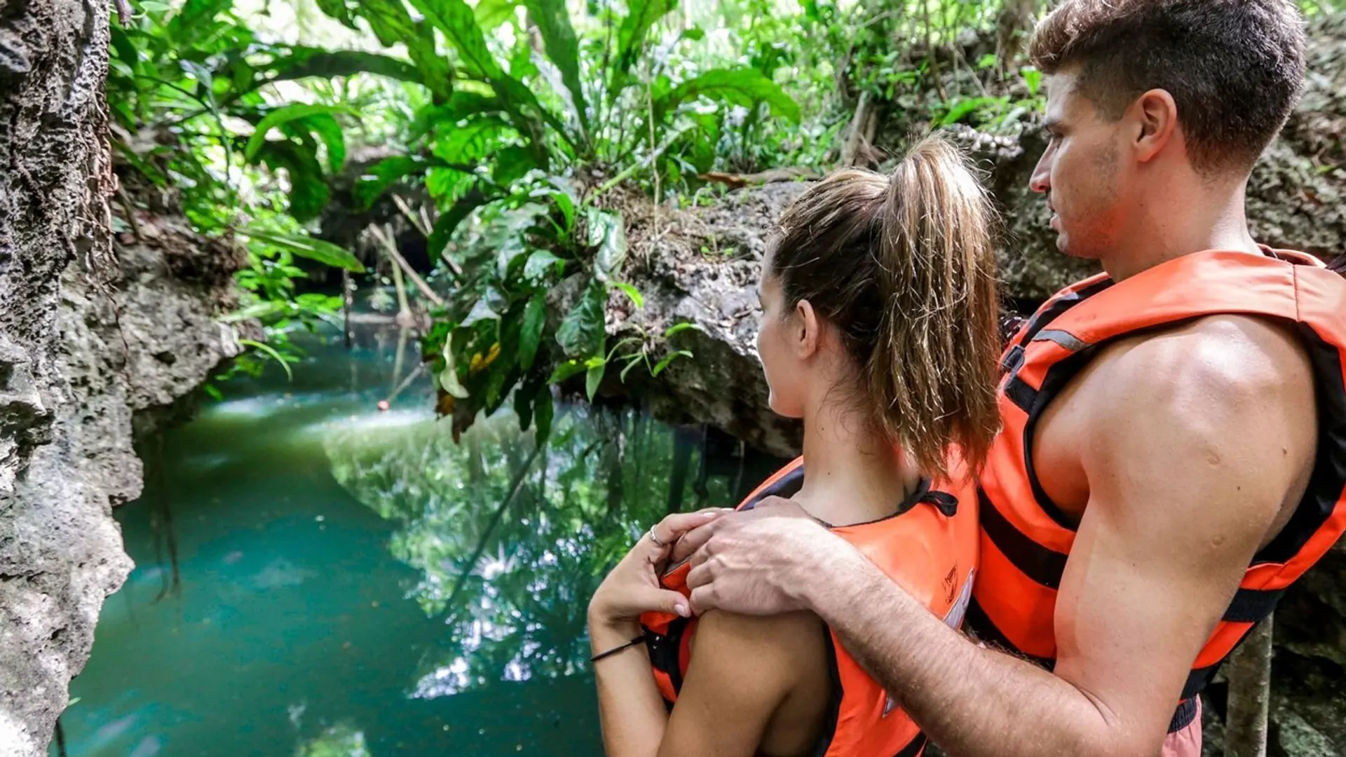Couple in life vests looking at a jungle cenote in Cozumel