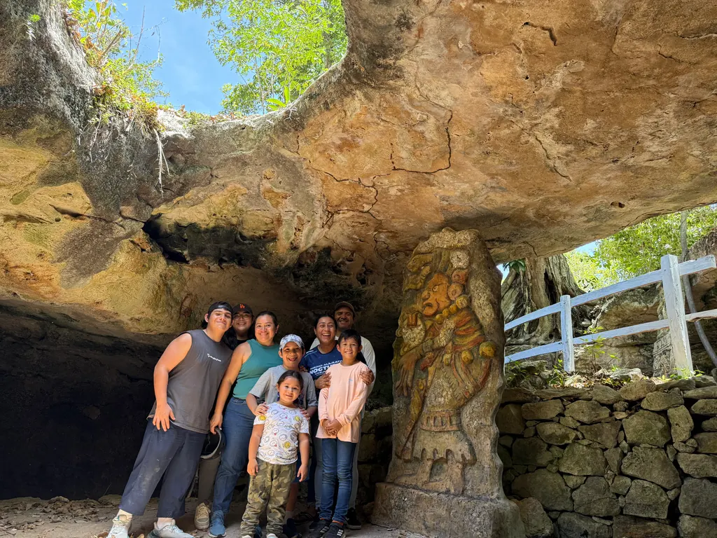 Family inside a Mayan cave with a carved stone figure